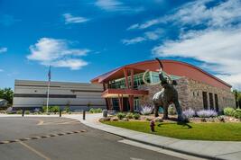 Photo of life-size bronze mammoth sculpture in front of museum building.
