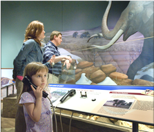Photo of guests viewing exhibit displays and listening to audio devices in the Ancient Basin
